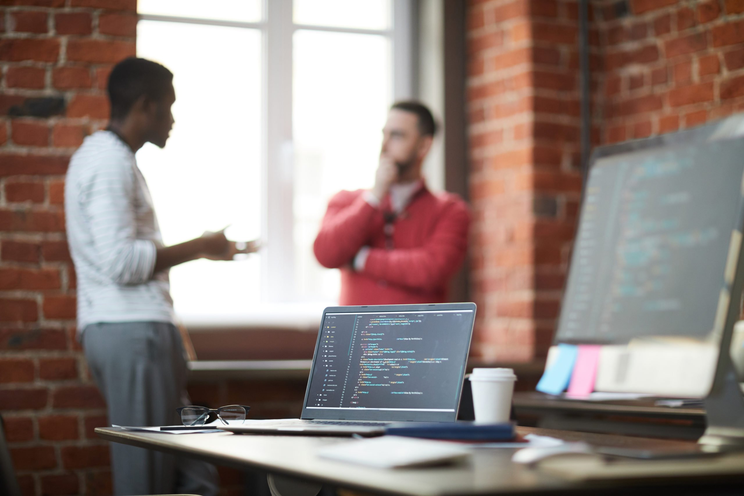 a man and a woman talking in a room with a laptop and a table