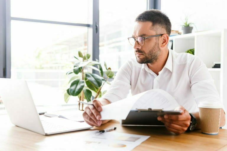 Portrait of smart businesslike man 30s in white shirt verifying